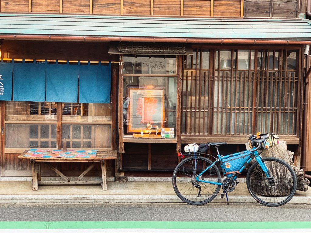 blue city bike parked beside brown wooden house during daytime