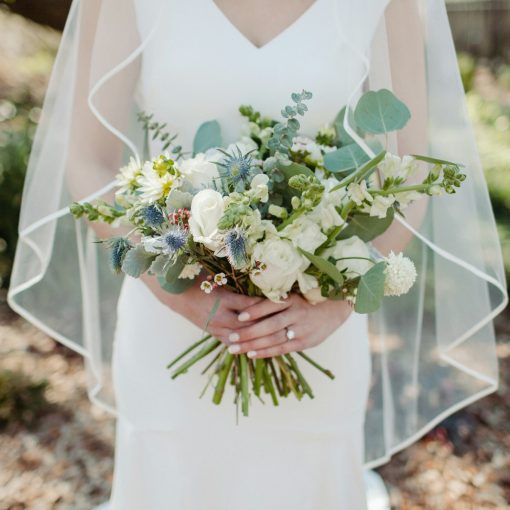 woman in white wedding dress holding white flower bouquet