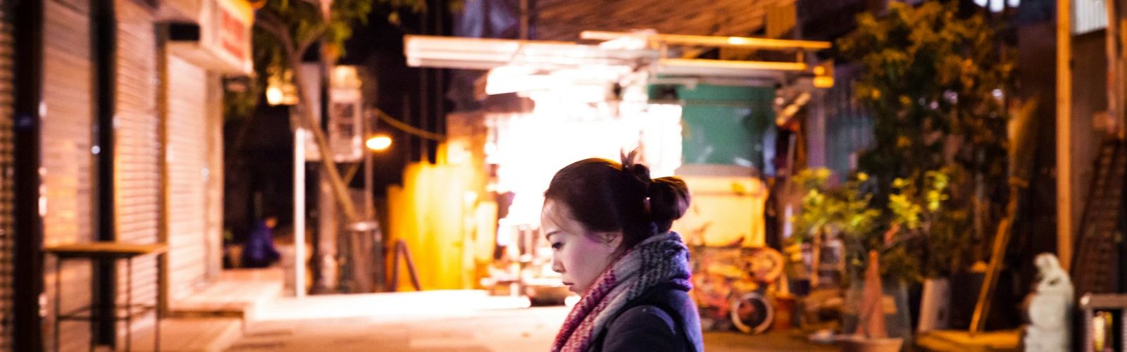 woman in black jacket sitting on red chair during night time