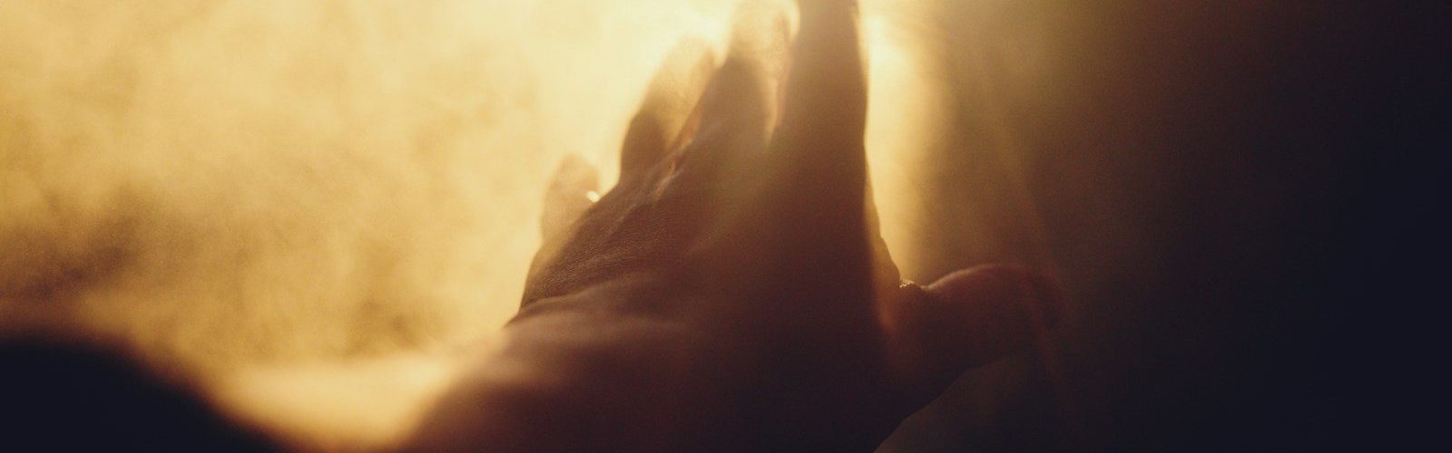 A hand reaching towards a bright light