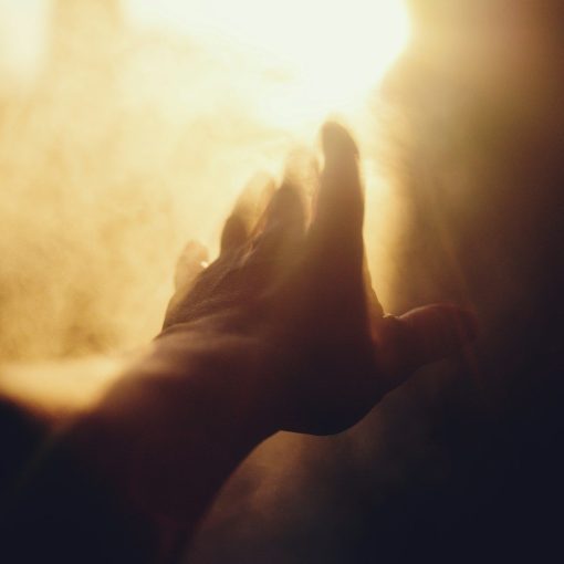 A hand reaching towards a bright light